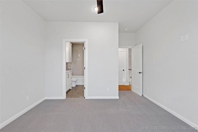 unfurnished bedroom featuring ensuite bathroom and light carpet