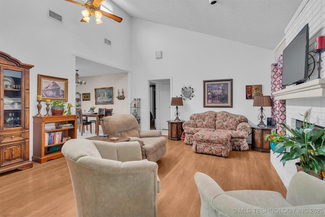 living room featuring a fireplace, vaulted ceiling, light hardwood / wood-style floors, and ceiling fan