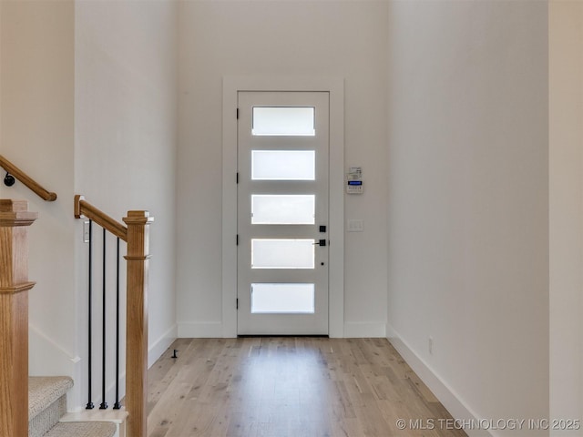 foyer featuring light wood-style floors, stairway, and baseboards