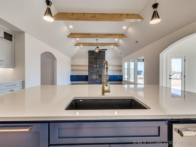 kitchen featuring pendant lighting, lofted ceiling with beams, sink, a kitchen island with sink, and ceiling fan