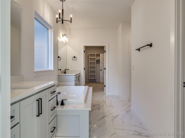 full bath featuring baseboards, a bath, marble finish floor, a spacious closet, and two vanities