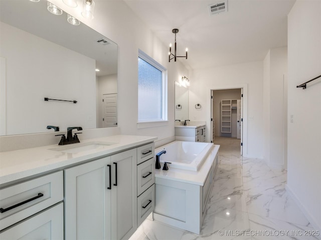 bathroom featuring vanity, a notable chandelier, and a tub