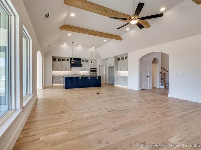 unfurnished living room featuring ceiling fan, beam ceiling, high vaulted ceiling, and light hardwood / wood-style flooring