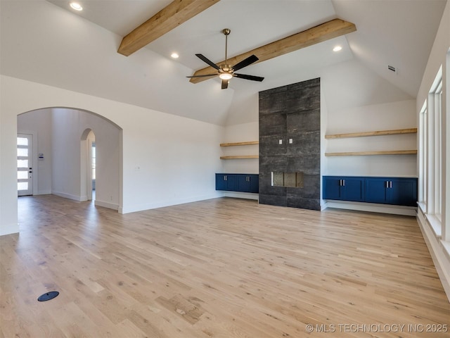 unfurnished living room featuring high vaulted ceiling, a fireplace, ceiling fan, light hardwood / wood-style floors, and beam ceiling