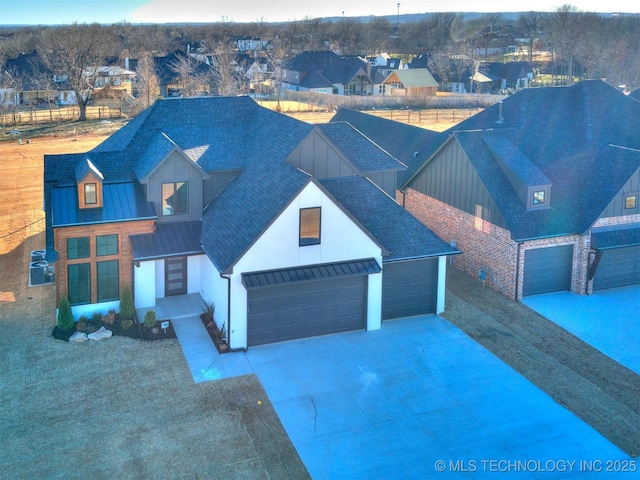 view of front facade with a garage, a standing seam roof, roof with shingles, and metal roof