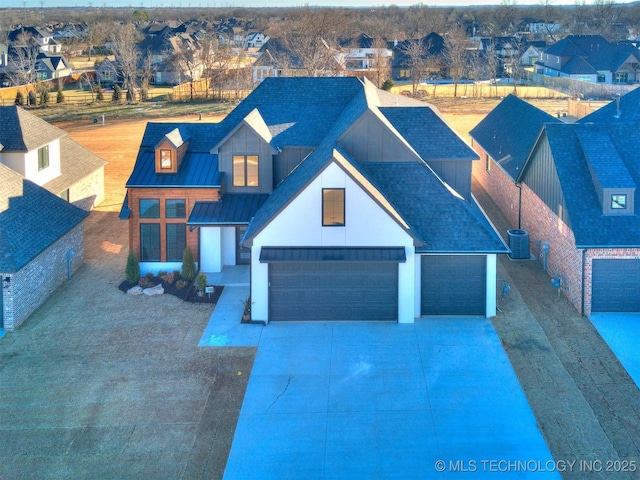 view of front of house with driveway, a residential view, metal roof, roof with shingles, and a standing seam roof