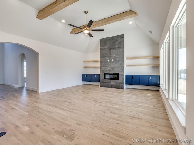 unfurnished living room with high vaulted ceiling, light wood-style flooring, a fireplace, visible vents, and beam ceiling