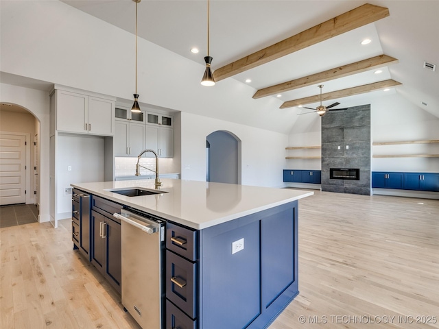 kitchen with light wood finished floors, arched walkways, pendant lighting, and a sink