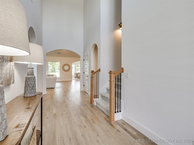 2508 E 135th Dr S, Bixby, OK 74008 - hall with arched walkways, light wood finished floors, a towering ceiling, baseboards, and stairs