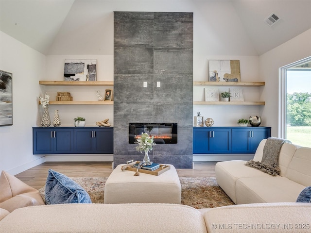 2508 E 135th Dr S, Bixby, OK 74008 - living area featuring lofted ceiling, light wood-type flooring, a tile fireplace, and baseboards