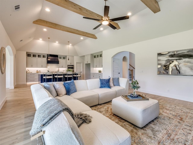 2508 E 135th Dr S, Bixby, OK 74008 - living room featuring arched walkways, beamed ceiling, light wood-type flooring, baseboards, and a ceiling fan