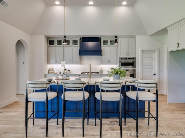 2508 E 135th Dr S, Bixby, OK 74008 - kitchen with custom exhaust hood, arched walkways, high vaulted ceiling, double oven, and tasteful backsplash