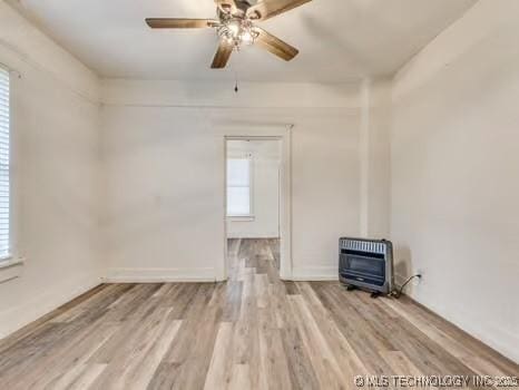 empty room featuring heating unit, light hardwood / wood-style flooring, and ceiling fan