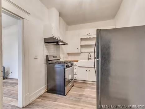 kitchen featuring stainless steel gas range, sink, white cabinetry, light hardwood / wood-style flooring, and black refrigerator