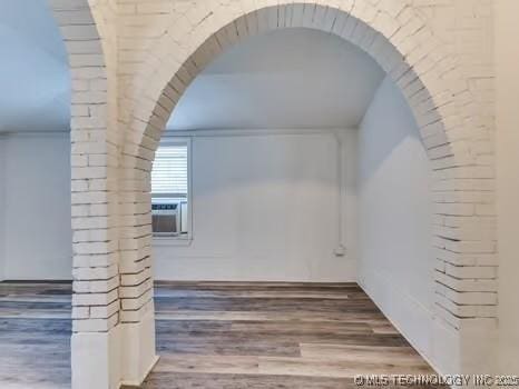 additional living space featuring cooling unit, brick wall, and hardwood / wood-style floors