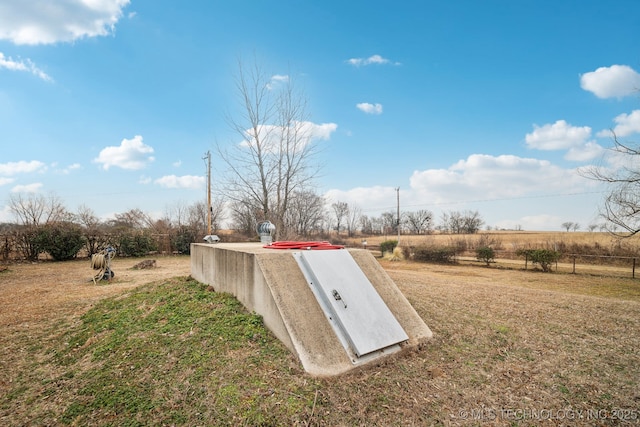 view of storm shelter featuring a rural view and a lawn