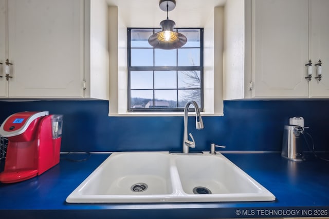 interior details featuring white cabinetry, decorative light fixtures, and sink