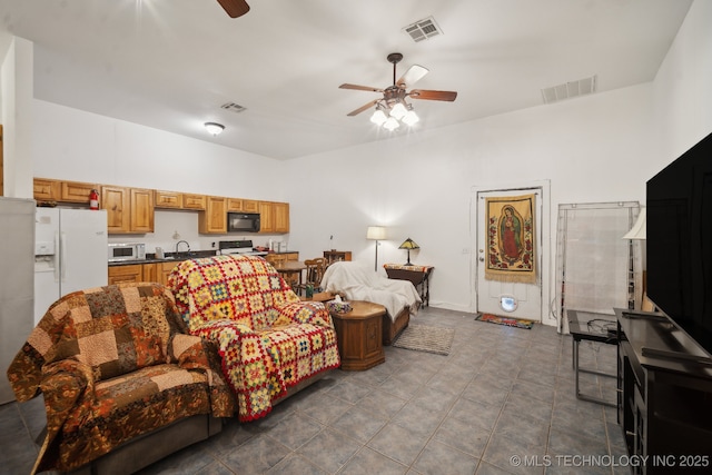 tiled living room with ceiling fan and sink