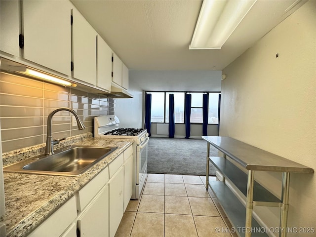 kitchen with light tile patterned flooring, white cabinetry, sink, decorative backsplash, and white gas range oven