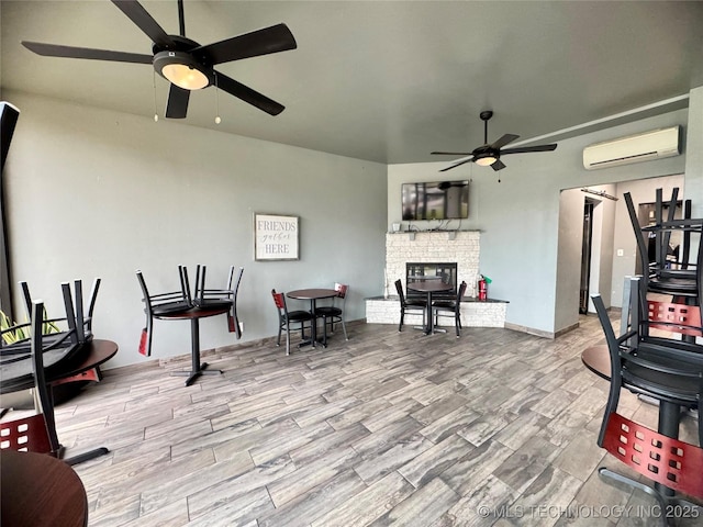 exercise area with ceiling fan, a wall mounted air conditioner, and light wood-type flooring