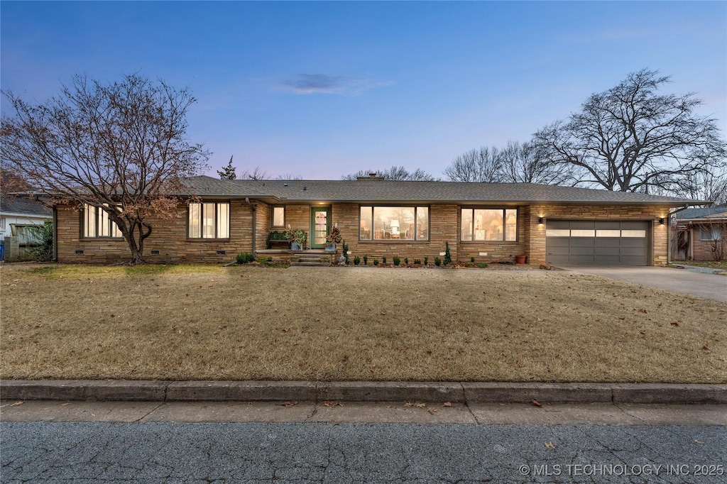 ranch-style home featuring a garage and a lawn