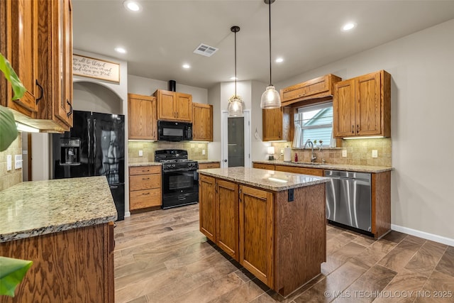 kitchen with a kitchen island, sink, hanging light fixtures, black appliances, and light stone countertops