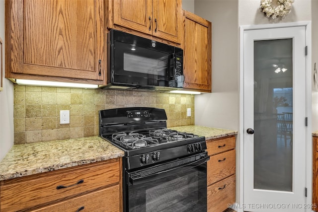 kitchen featuring backsplash, light stone countertops, and black appliances