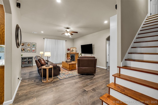 living room featuring dark wood-type flooring and ceiling fan