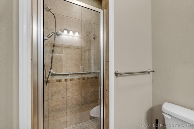 bathroom featuring toilet and a shower with door