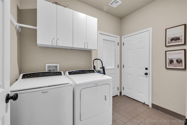 washroom featuring cabinets, washing machine and clothes dryer, and light tile patterned flooring