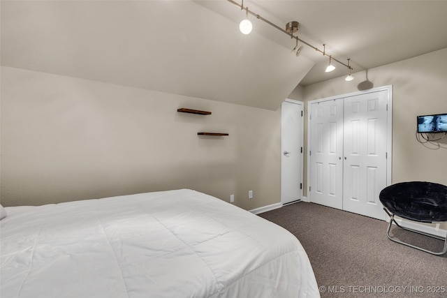 carpeted bedroom featuring rail lighting, vaulted ceiling, and a closet