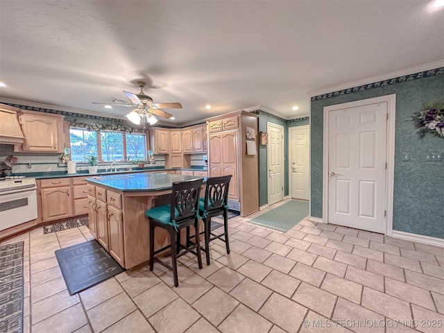 kitchen featuring a breakfast bar area, light tile patterned flooring, light brown cabinets, stove, and a center island