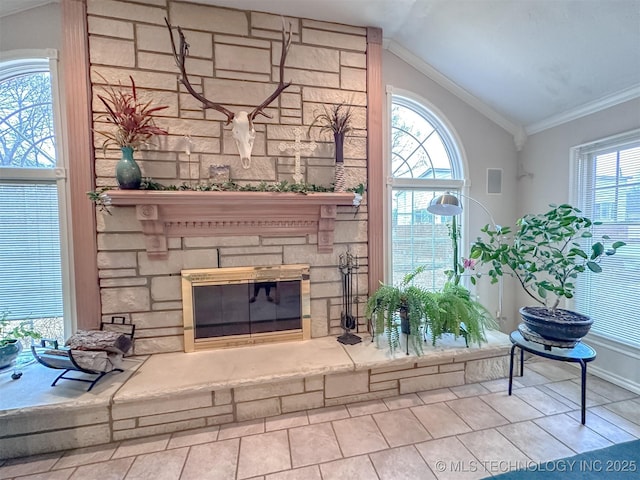 living room with vaulted ceiling, a stone fireplace, plenty of natural light, and crown molding