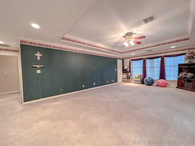 interior space with visible vents, a tray ceiling, a ceiling fan, and ornamental molding