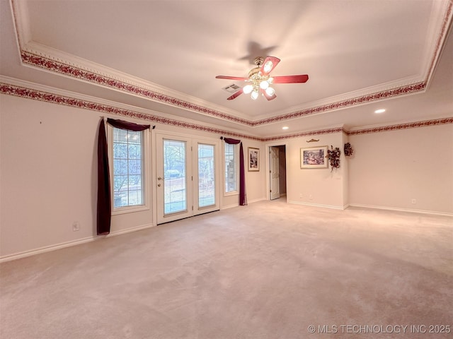 spare room with a raised ceiling, light colored carpet, and crown molding