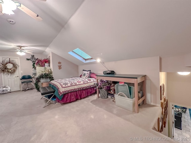 bedroom with carpet floors, vaulted ceiling with skylight, and a ceiling fan