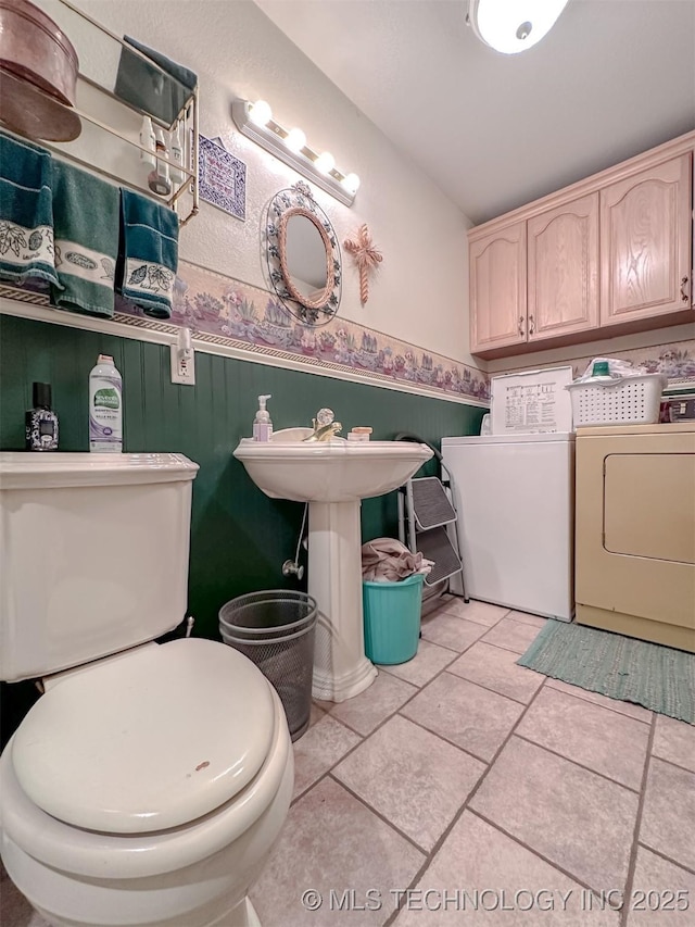 half bathroom with a wainscoted wall, toilet, and washer and dryer