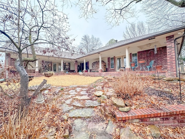 back of property featuring covered porch and brick siding