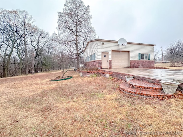 exterior space with an attached garage, a lawn, and brick siding