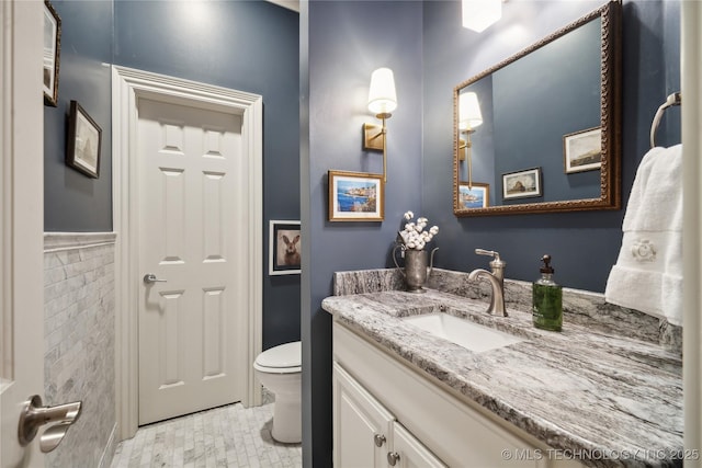 bathroom with vanity, toilet, and tile walls