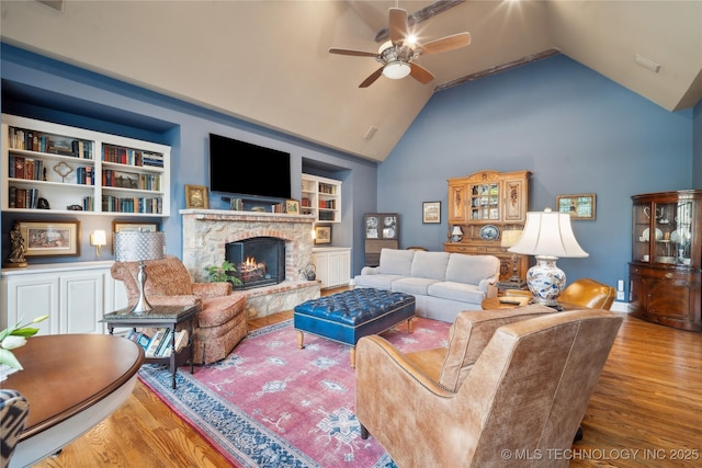 living room with wood-type flooring, high vaulted ceiling, built in features, and ceiling fan