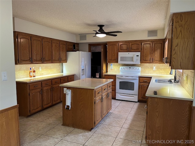 kitchen with light tile patterned flooring, sink, white appliances, a center island, and ceiling fan