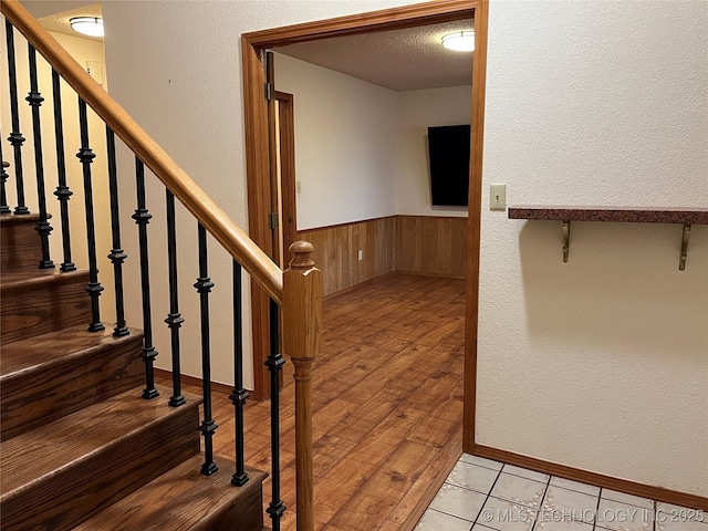 stairs featuring wood-type flooring, a textured ceiling, and wood walls