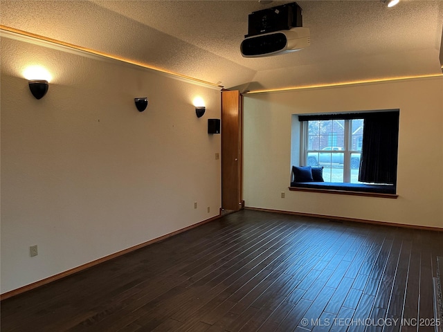 empty room with dark hardwood / wood-style flooring, vaulted ceiling, and a textured ceiling