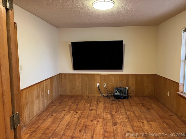 empty room featuring wood walls, light hardwood / wood-style flooring, and a textured ceiling