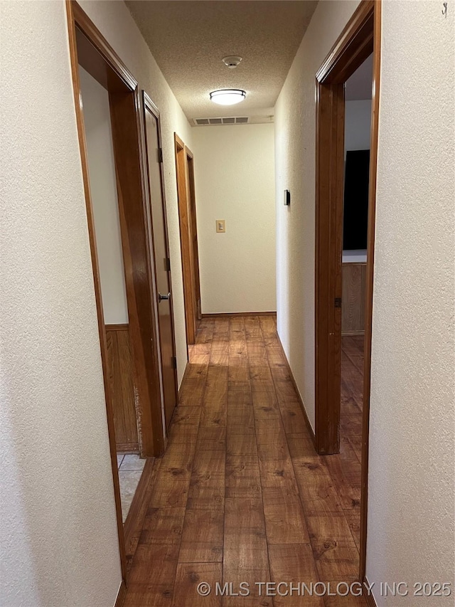 corridor featuring hardwood / wood-style floors and a textured ceiling