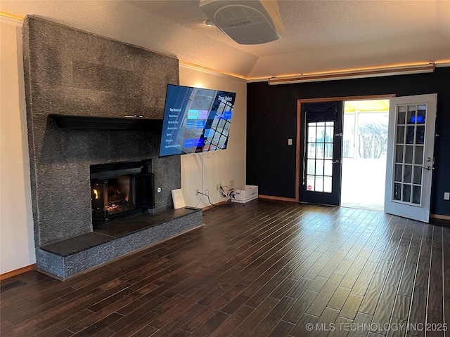 unfurnished living room featuring a fireplace, dark hardwood / wood-style floors, vaulted ceiling, and a textured ceiling