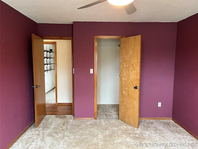 unfurnished bedroom with ceiling fan, light colored carpet, and a textured ceiling