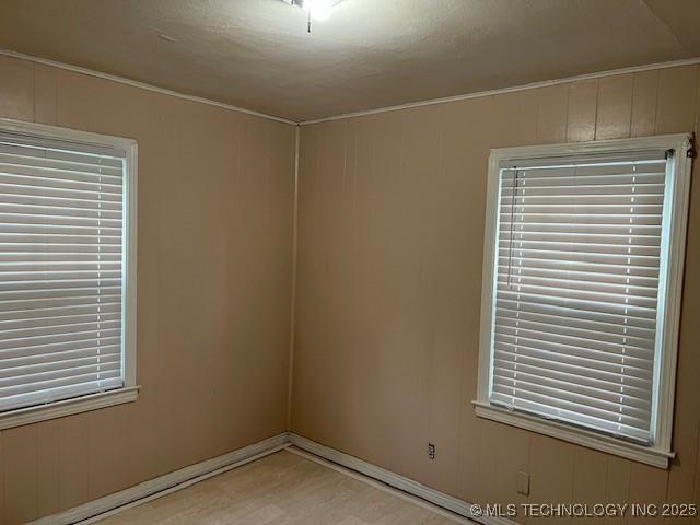 spare room featuring light wood-type flooring and ornamental molding