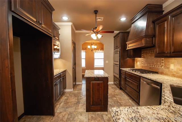 kitchen featuring a kitchen island, appliances with stainless steel finishes, tasteful backsplash, light stone countertops, and custom range hood